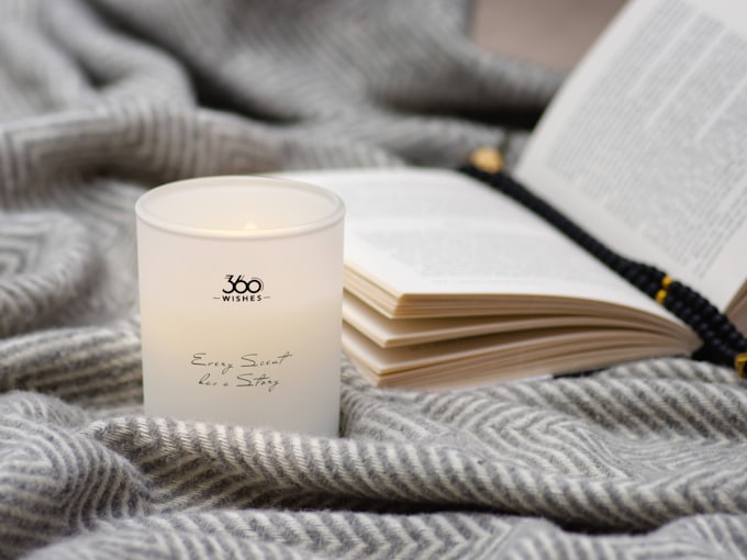 A candle and an open book on a soft blanket